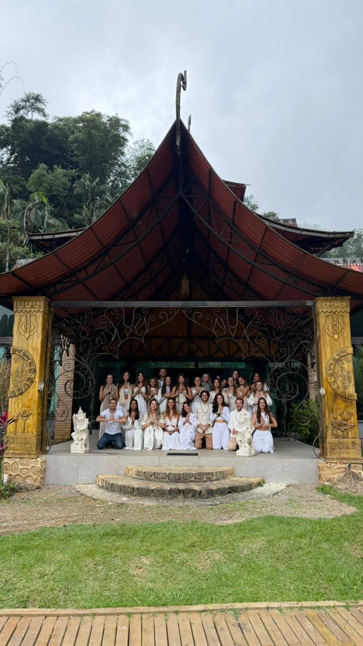 Turma da formação Yoganaya reunida sob o telhado vermelho, com as mãos em prece