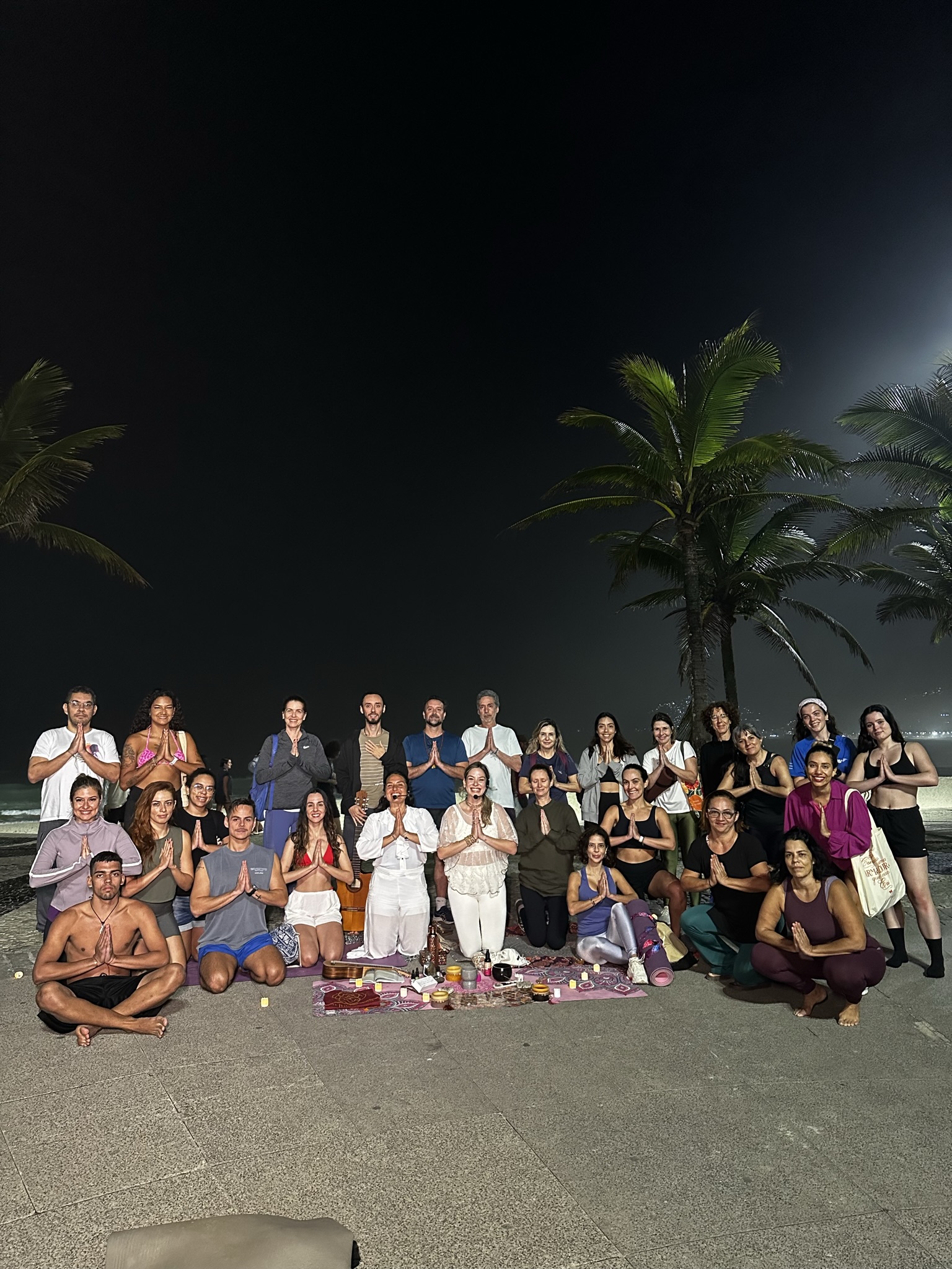Participantes reunidos com as mãos em prece no encerramento do Maha Karma no Arpoador